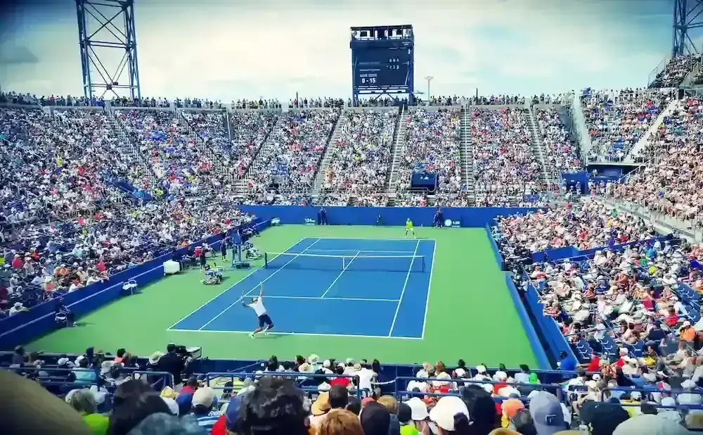 A tennis player serves during a match in a crowded stadium.