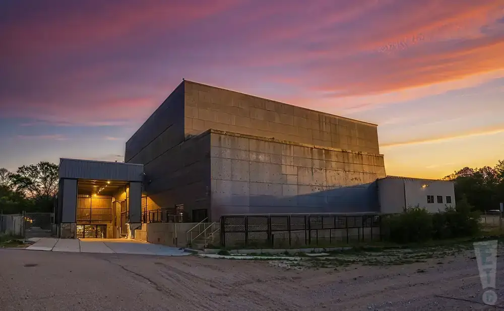 A concrete building under a dramatic pink and orange sunset sky.