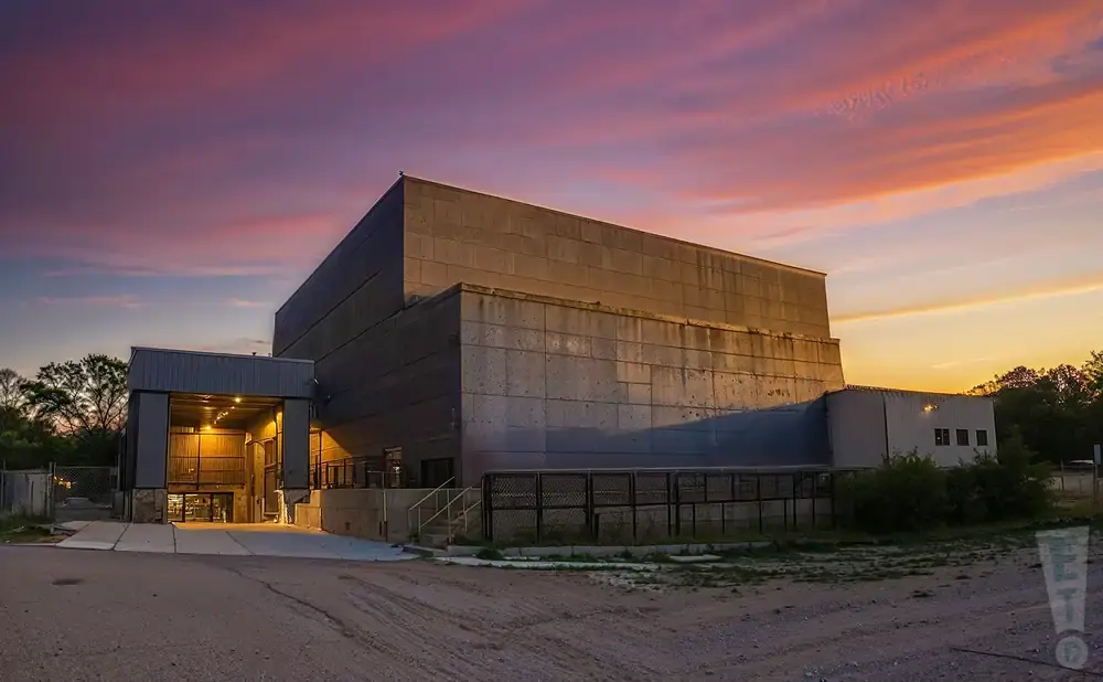 A brutalist concrete building at sunset with a vibrant pink and orange sky.