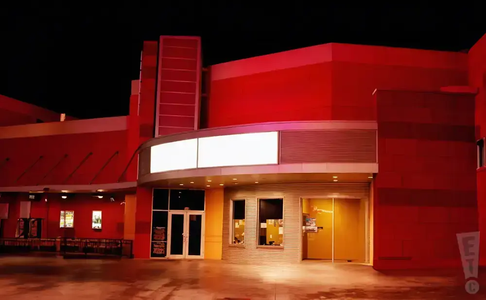 Red movie theater entrance at night with blank marquee signs.