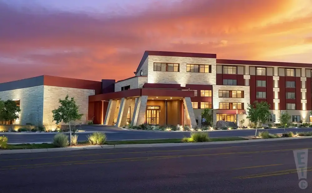 A modern hotel with stone and maroon accents at sunset.