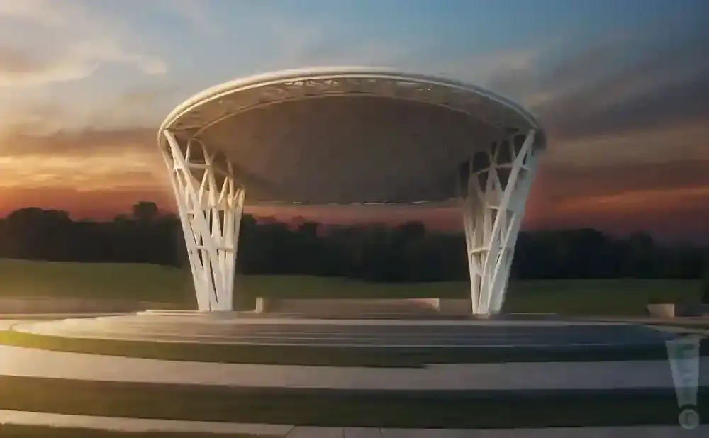 An outdoor amphitheater with a white, modern roof supported by sculptural pillars, set against a sunset sky.