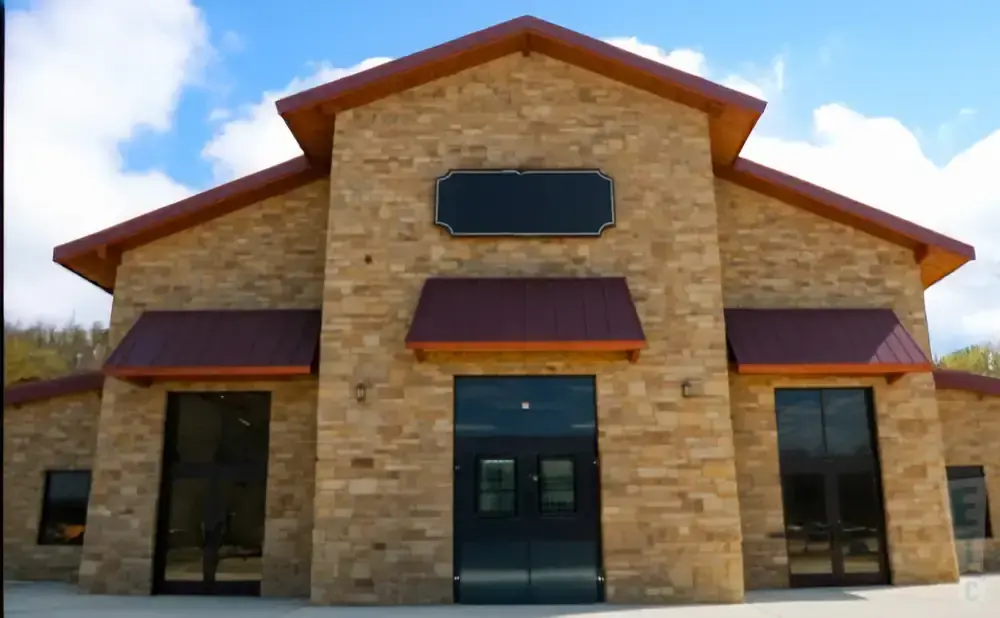 A stone building with a red roof and large glass doors.