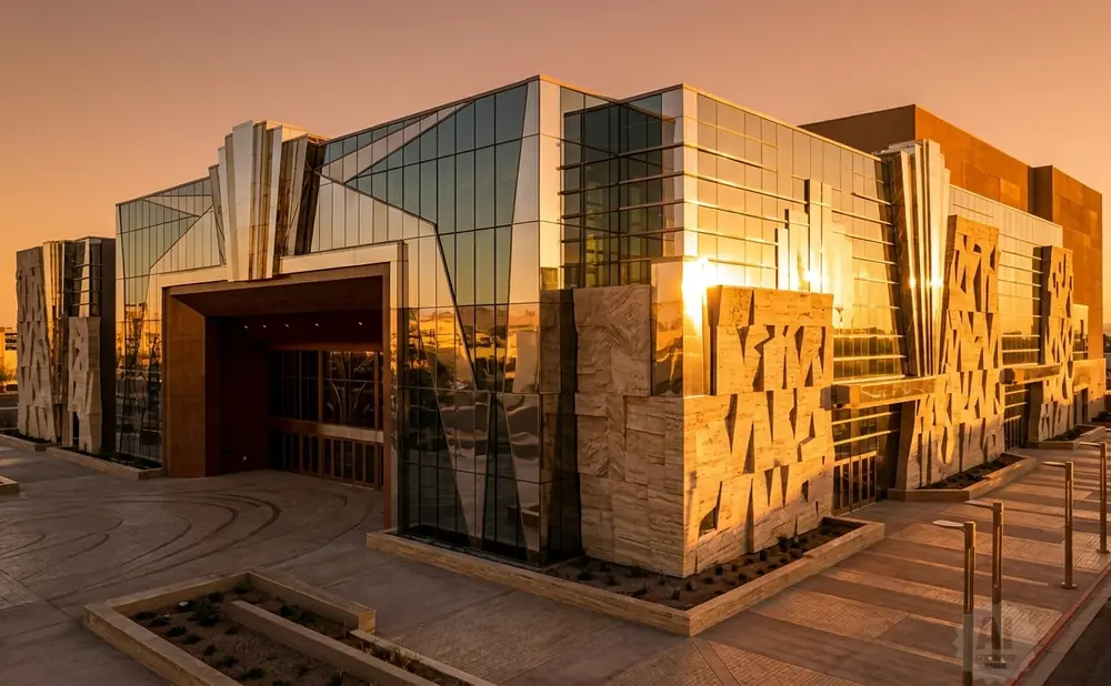 Modern building with glass facade and stone accents reflecting sunset.