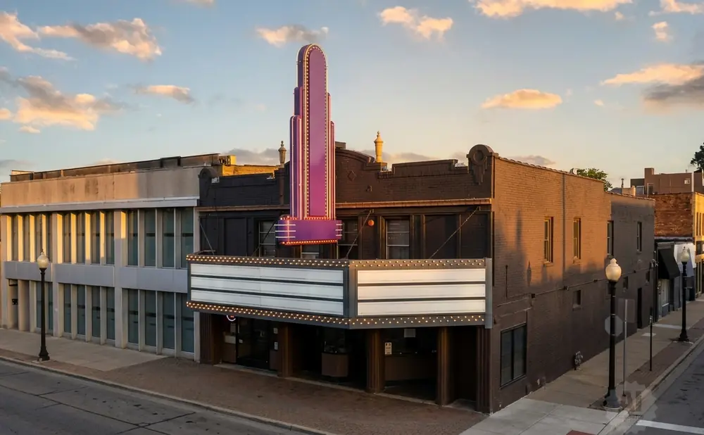 Art Deco theater with a purple neon marquee at sunset.