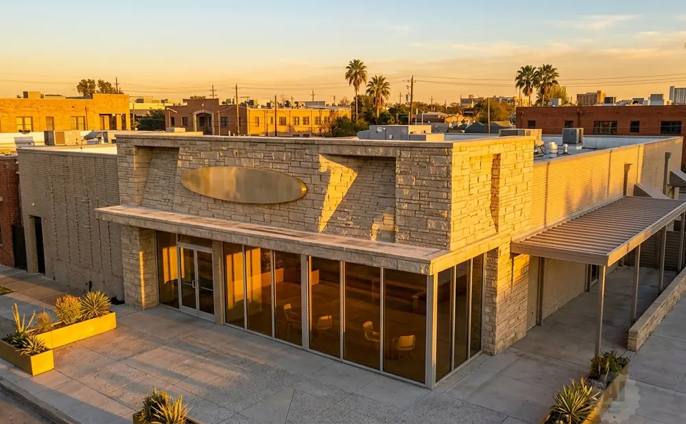Modern storefront with stone facade and large windows, bathed in golden sunset light.