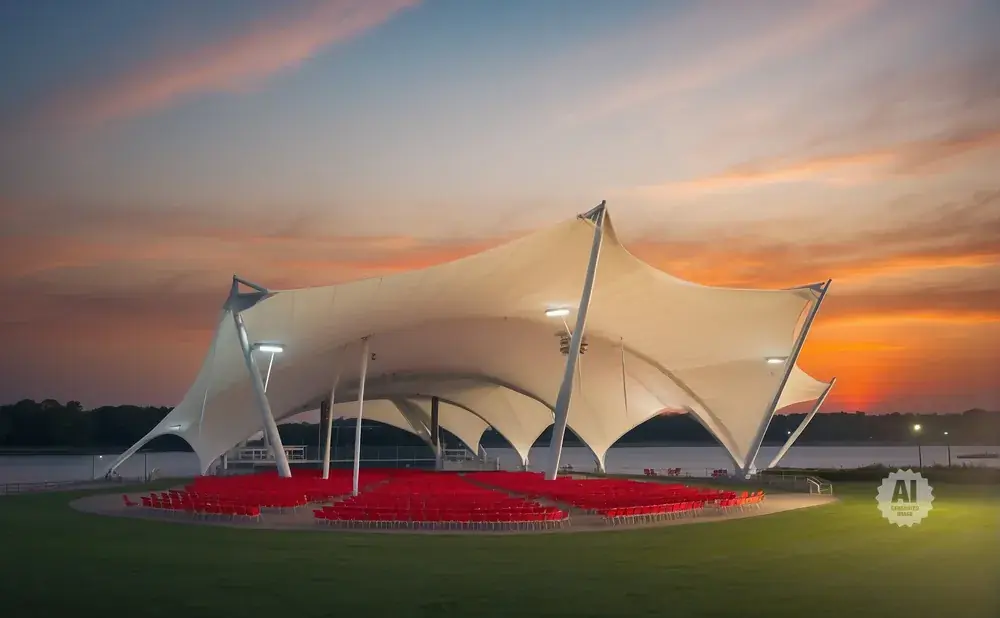 Outdoor amphitheater with red seats under a large white tent at sunset.