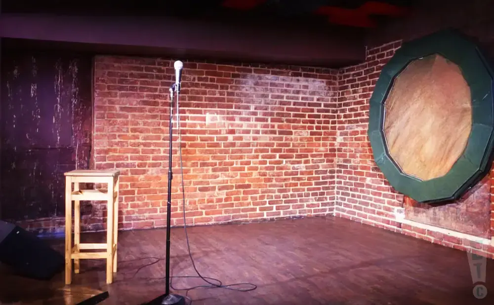 A brick wall backdrop for a performance stage with a stool and microphone.