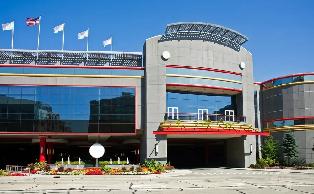 Modern building with large glass windows, flags, and colorful flowerbeds.