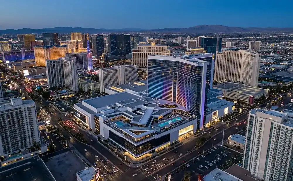 Aerial view of Las Vegas Strip hotels and casinos at dusk, with illuminated buildings and city lights.