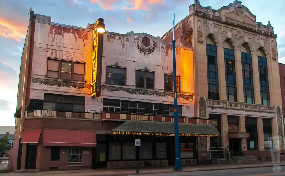 Art deco theater building with a marquee and glowing neon sign, illuminated by sunset light.