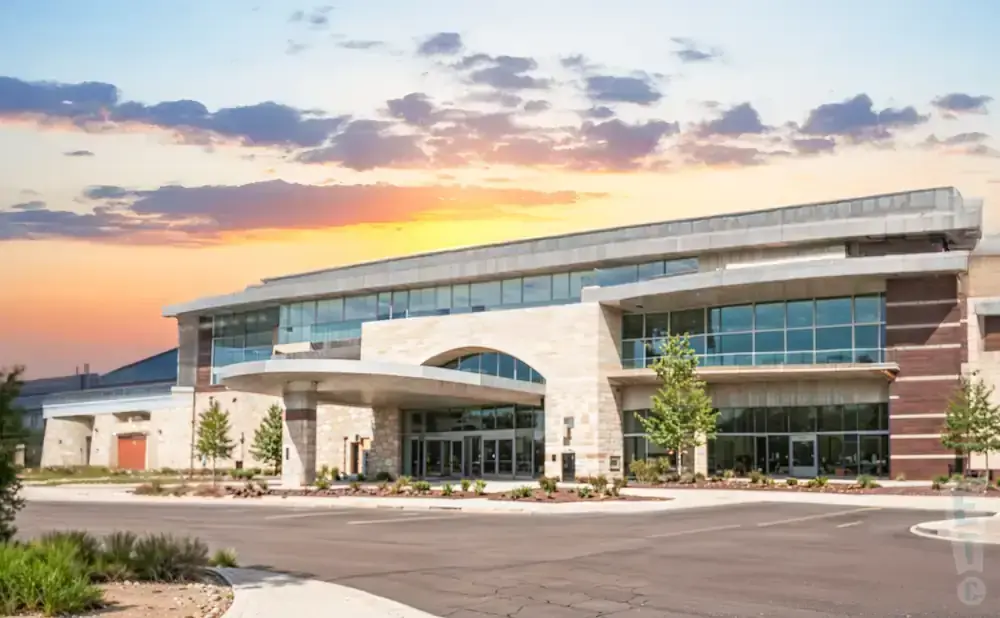 Modern building with arched entrance and large glass windows during a colorful sunset.