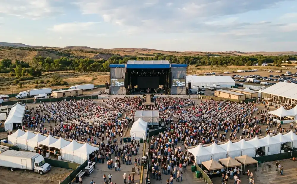 Aerial view of an outdoor concert with a large stage, seated audience, and tents.