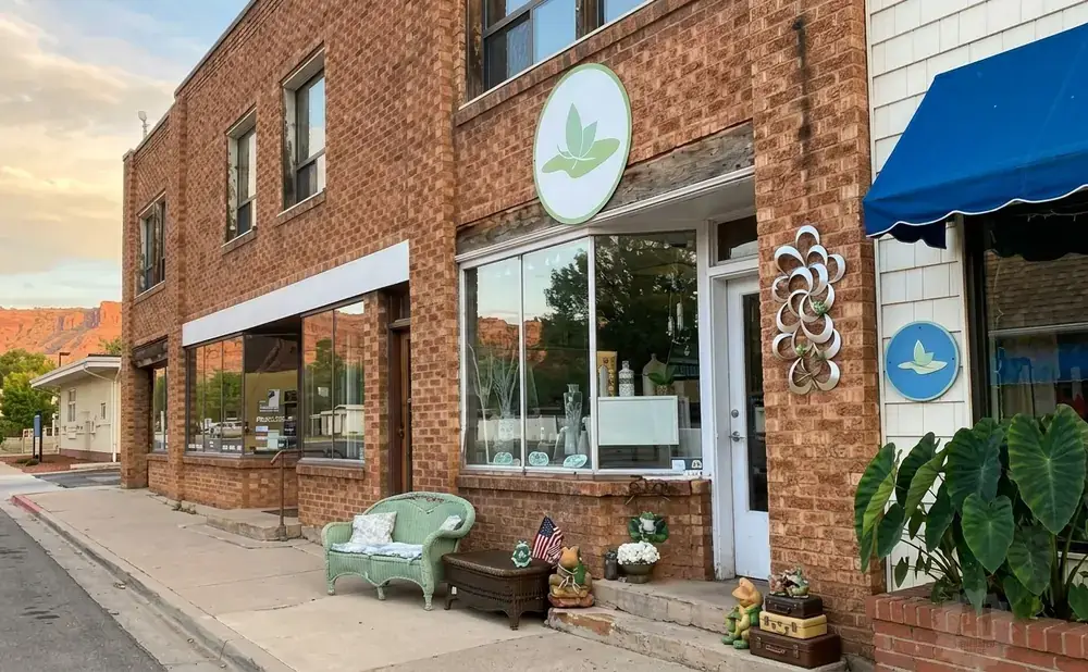 A brick storefront with a blue awning and signs featuring a green leaf logo.