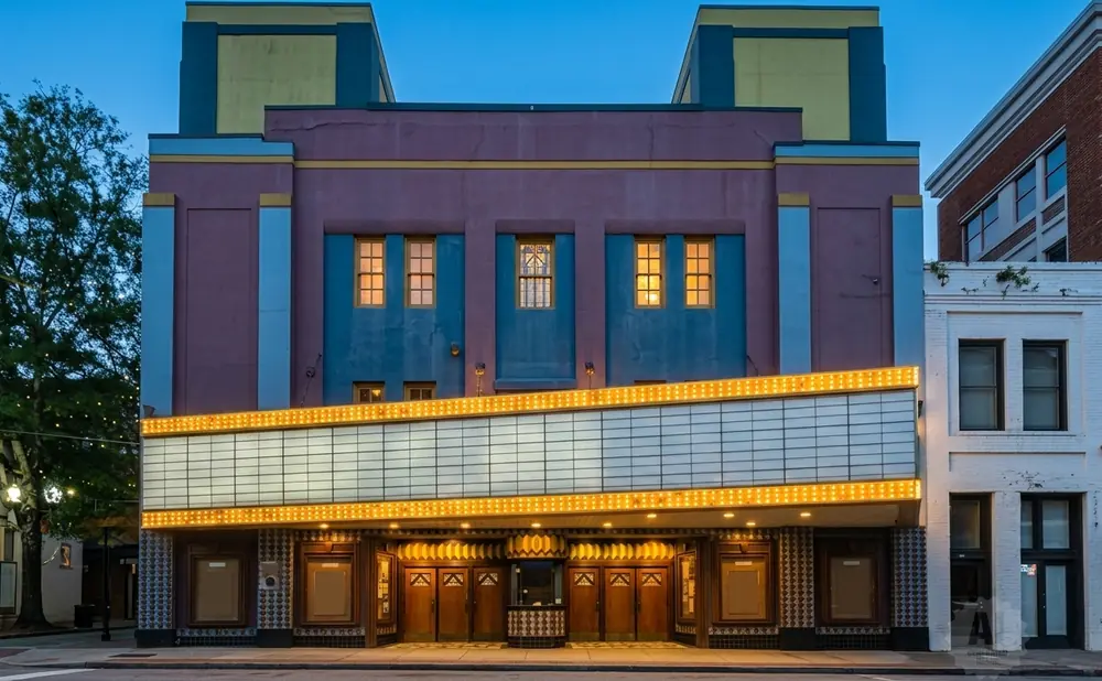 Art Deco theater with a marquee and marquee lights, at dusk.