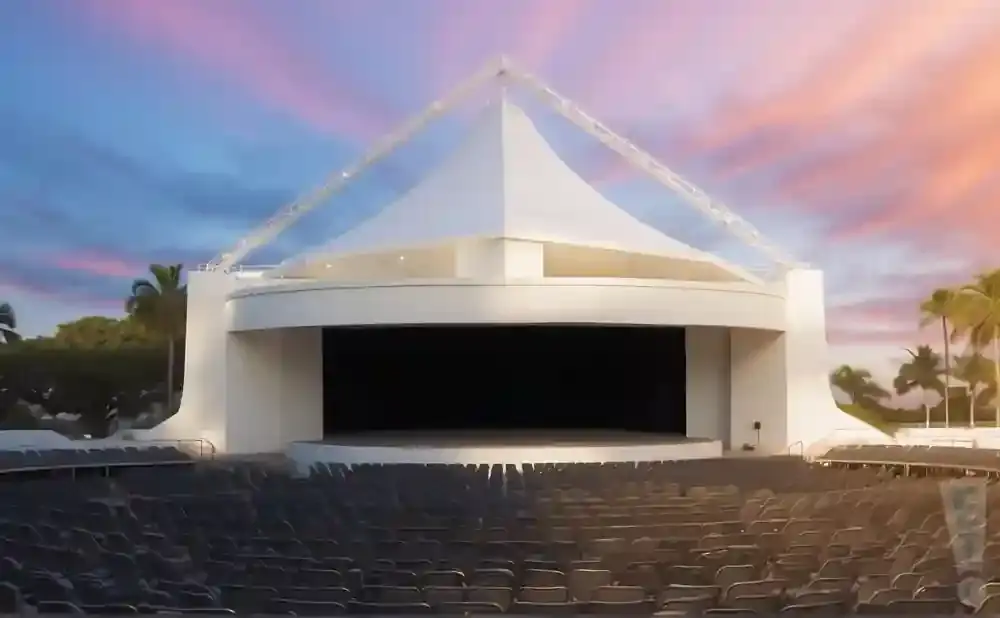 Outdoor amphitheater stage with rows of empty seats and a colorful sunset sky.