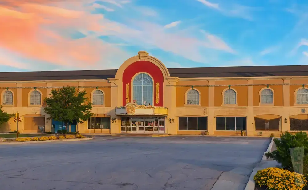 A movie theater with an arched red entrance and marquee, under a colorful sunset sky.