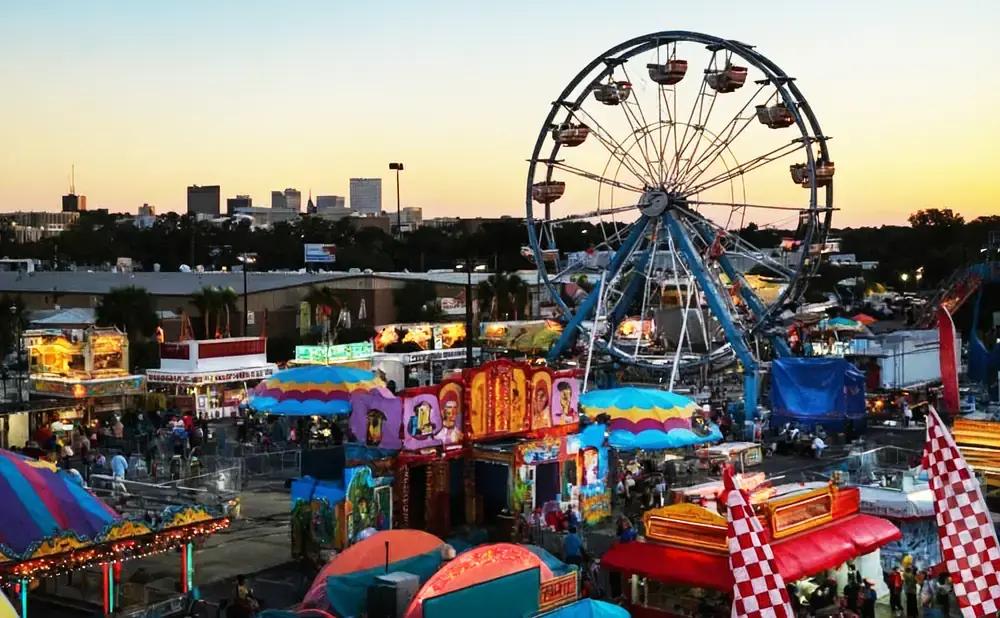 An amusement park with a Ferris wheel and colorful rides under a sunset sky.