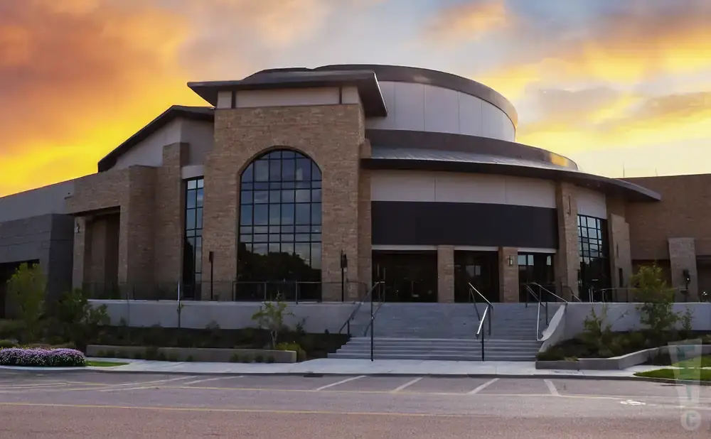 Modern building with stone accents and arched windows under a vibrant sunset sky.