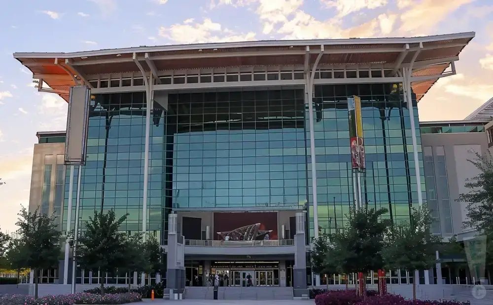 Modern glass-fronted convention center with large roof overhang and surrounding trees.