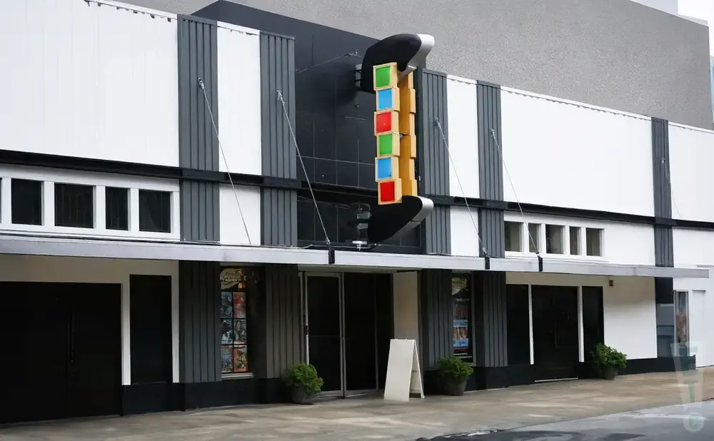 Exterior of a modern cinema with a vertical marquee displaying colored squares.