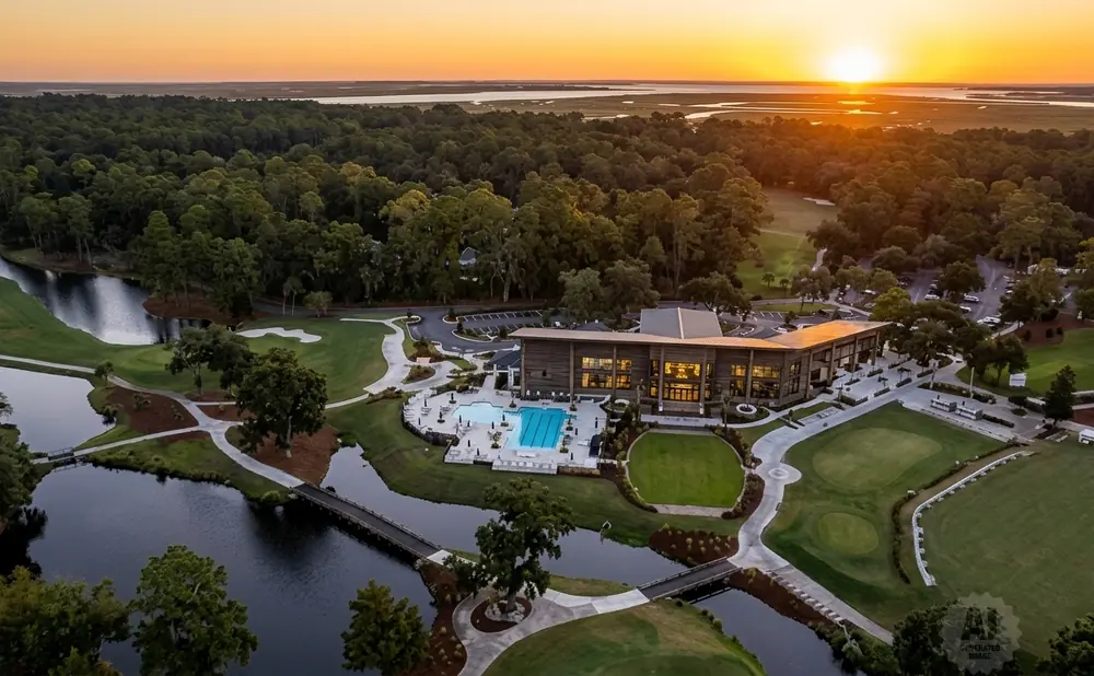 Aerial view of a golf course club house and pool at sunset.