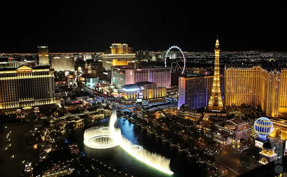 Las Vegas Strip at night, featuring the Eiffel Tower replica, the High Roller observation wheel, and the Bellagio fountains.