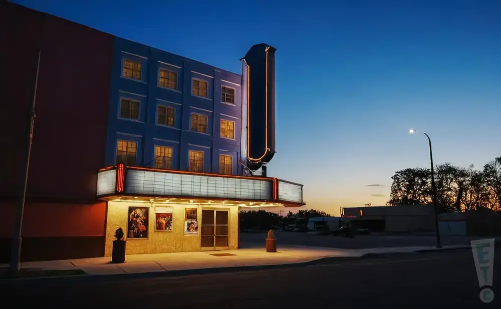 A retro movie theater facade glows under a twilight sky.