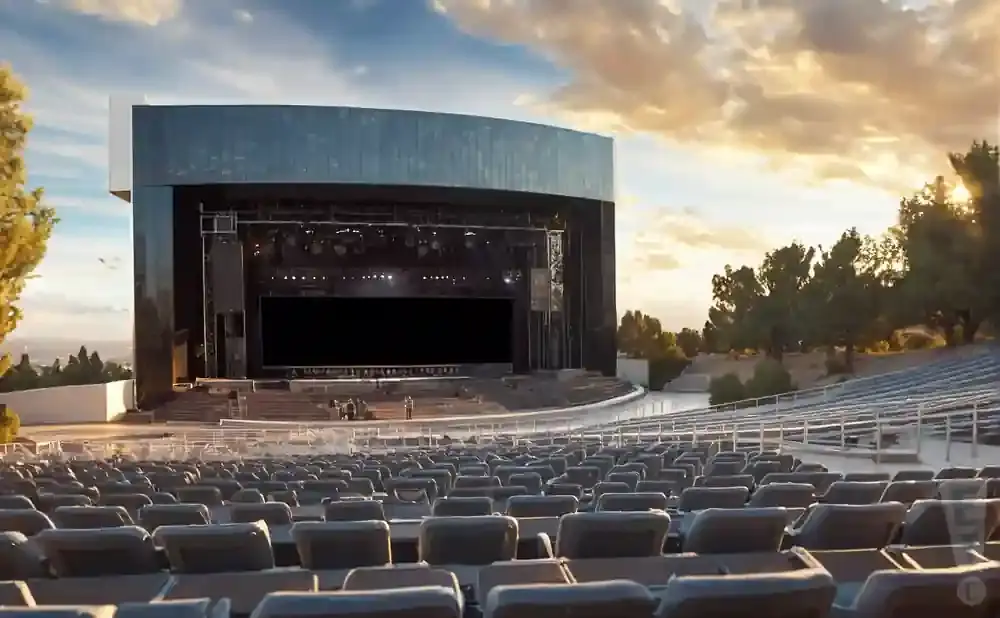 Outdoor amphitheater stage at sunset with rows of empty seats in the foreground.