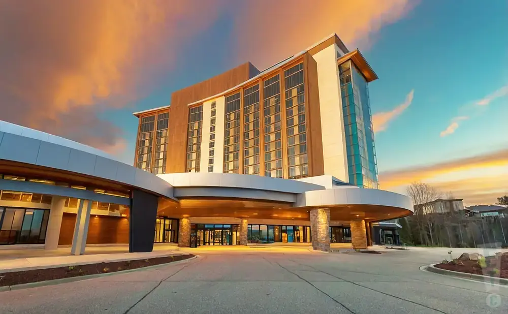 Modern hotel entrance with curving canopy and sunset sky.