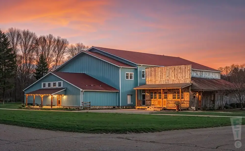 A light blue barn with a red roof at sunset.