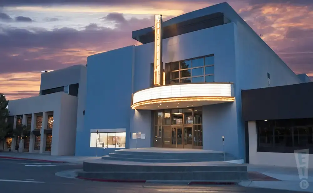 A blue theater with a lit marquee at dusk.