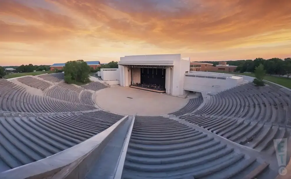 An outdoor amphitheater at sunset with rows of seats facing a stage.