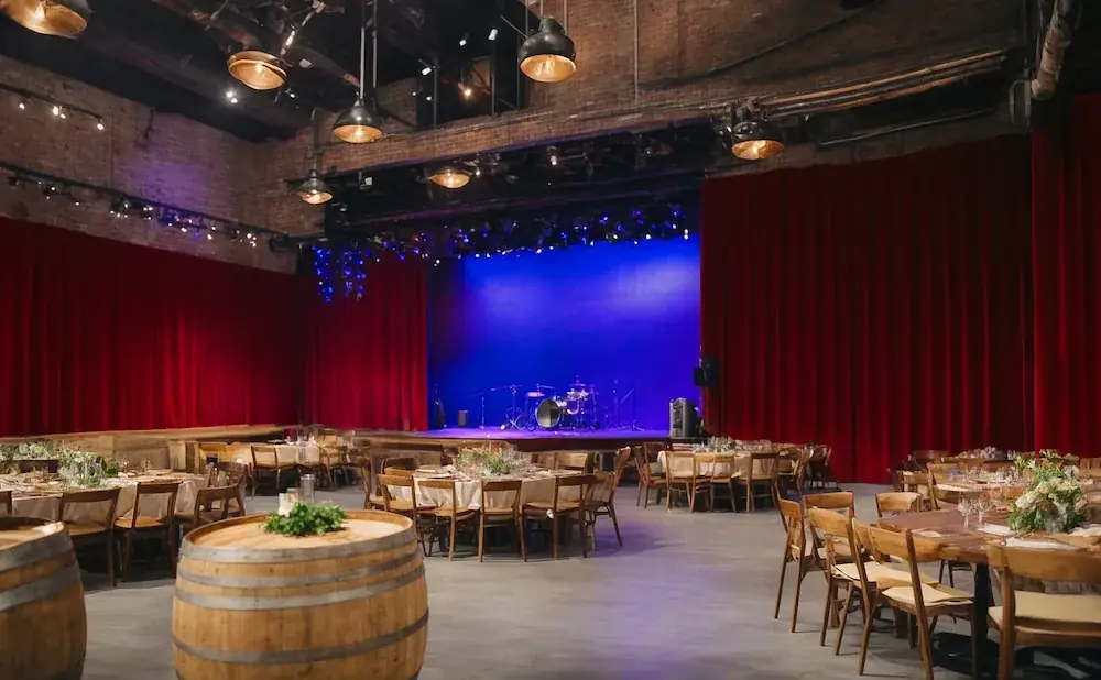 Banquet hall with stage, red curtains, and tables set for a meal.