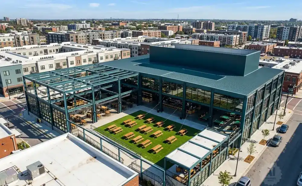 Aerial view of a modern building with a large open-air courtyard filled with picnic tables and a green lawn.