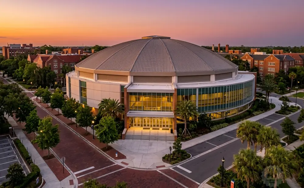 Aerial view of a circular, domed arena on a university campus at sunset.