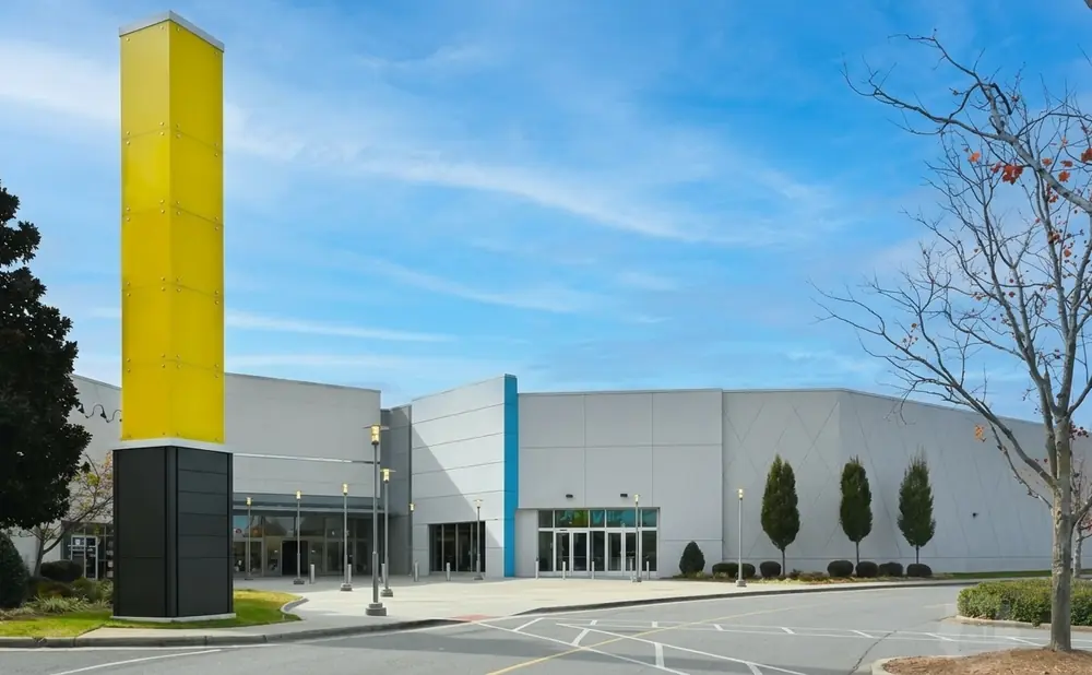 A yellow and black tower stands in front of a modern building with a blue accent.