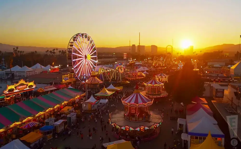 Sunset over a vibrant carnival with a Ferris wheel and carousels.