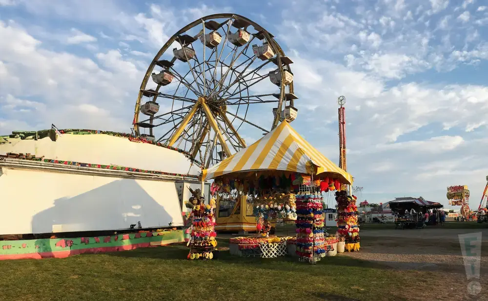 Ferris wheel and carnival games under a cloudy sky.