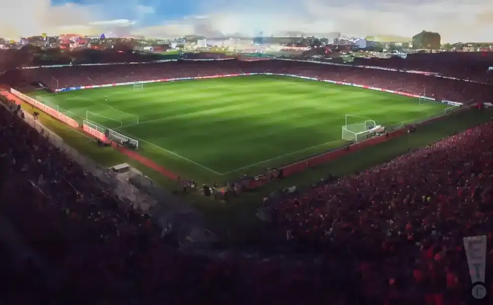 An aerial view of a soccer stadium filled with cheering fans at dusk.