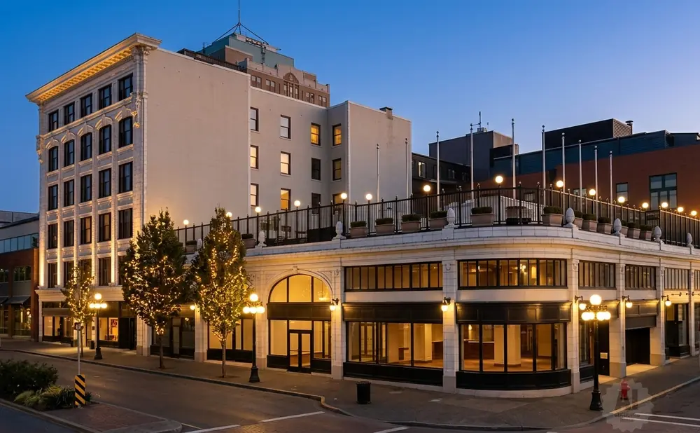 A historic downtown building at dusk, lit by streetlights and decorative lights on trees.