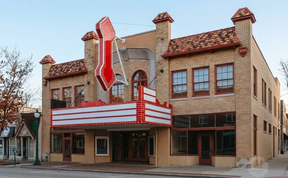 Retro movie theater with a marquee sign and brick facade on a sunny day.