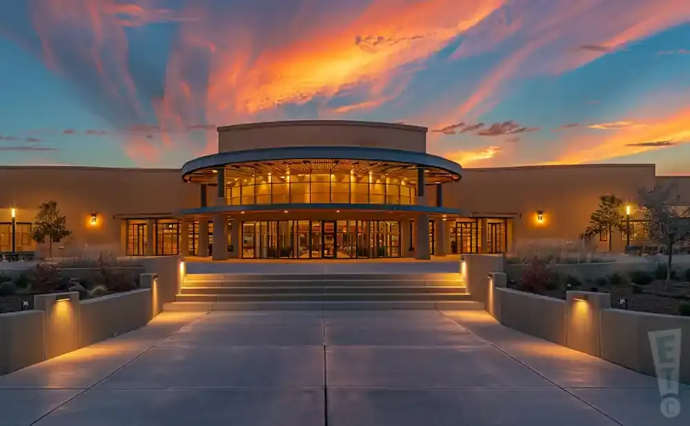 Modern building entrance with grand staircase at sunset with dramatic orange and pink clouds.