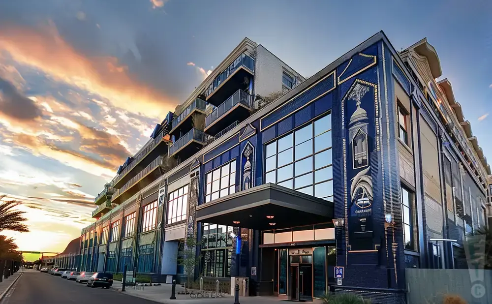 A modern building with blue tiled facade and balconies against a dramatic sunset sky.