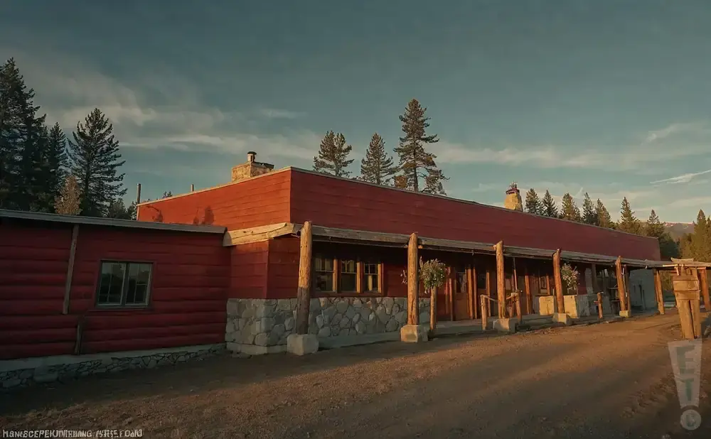 A long, red wooden building with a stone foundation and a covered porch.