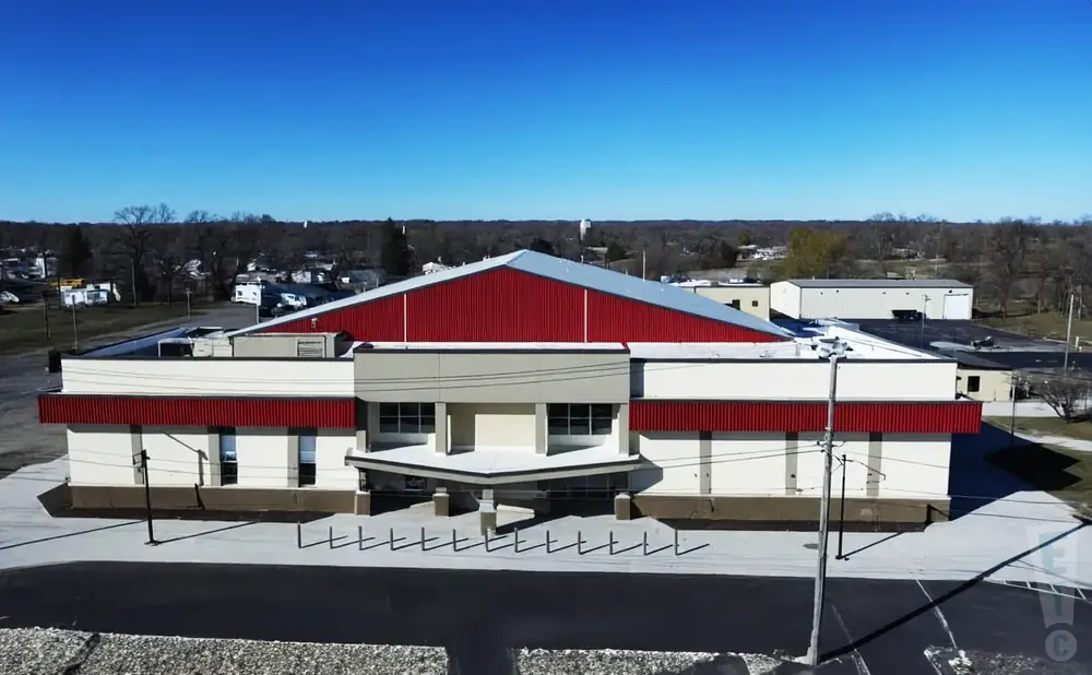 Aerial view of a modern building with a red, pitched roof and cream-colored walls.