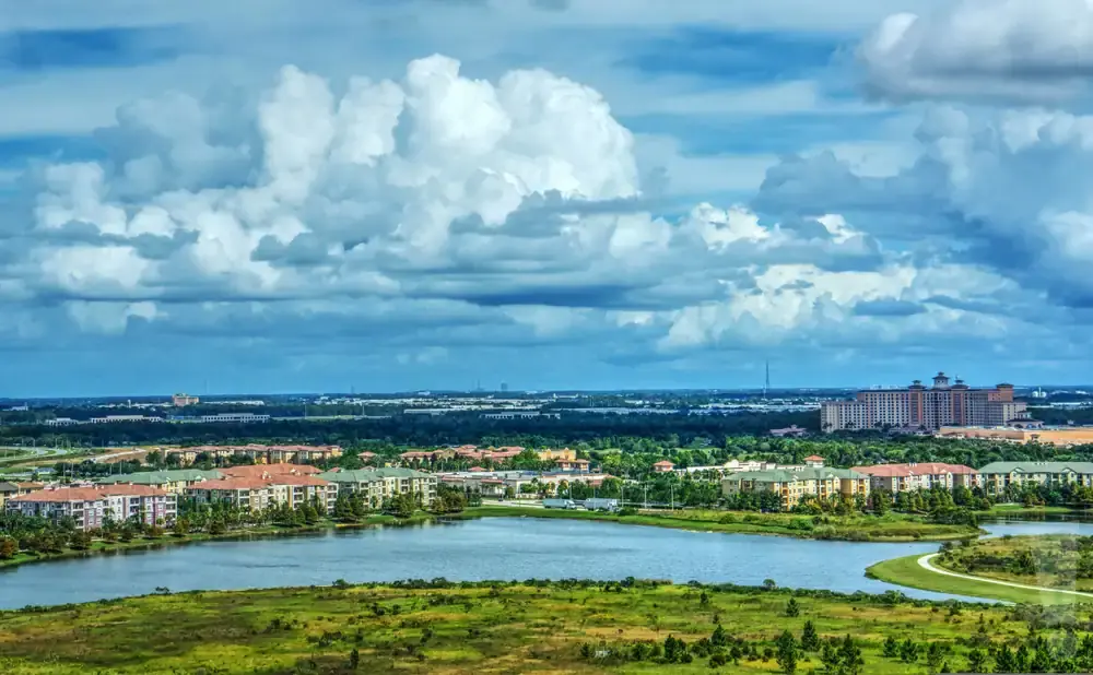 A wide shot of a lake with colorful apartment buildings and a large hotel in the background under a cloudy sky.