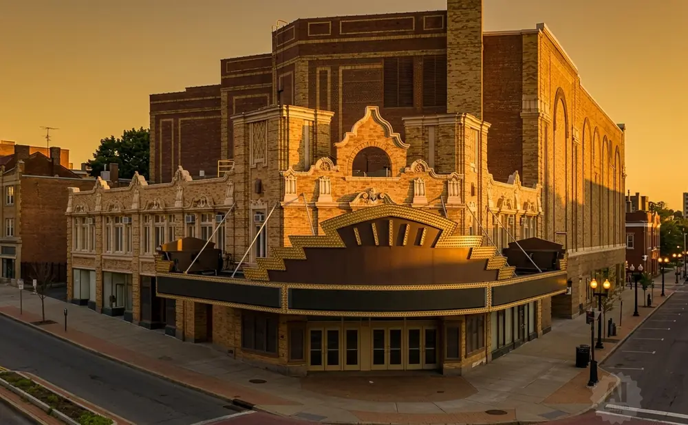 Marquee of an ornate theater with a golden arch illuminated by sunset glow.