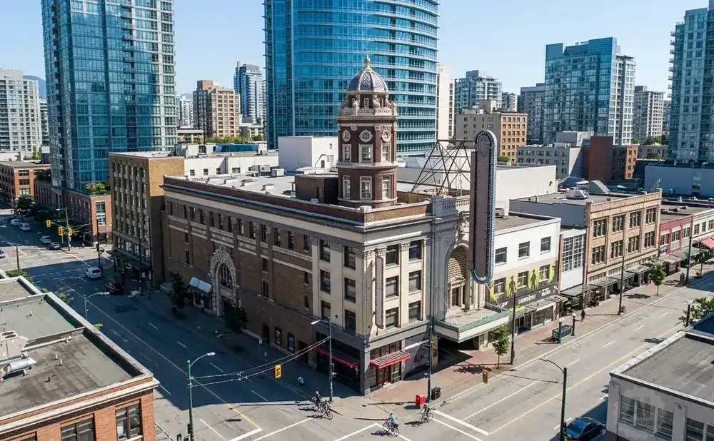 Aerial view of a city street with historic buildings, modern skyscrapers, and people cycling.