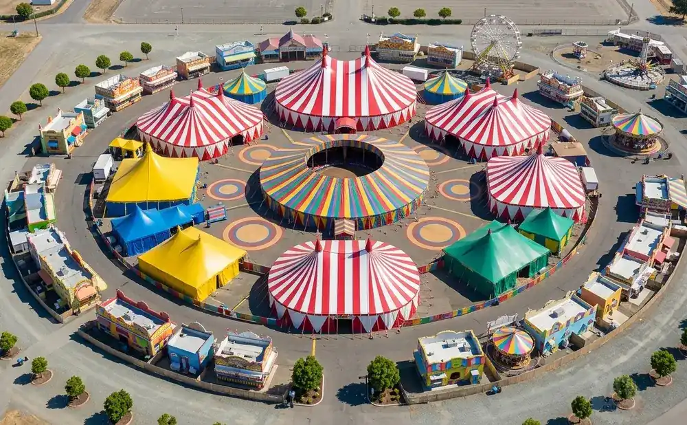Aerial view of a carnival with circus tents, rides, and games arranged in a circular layout.